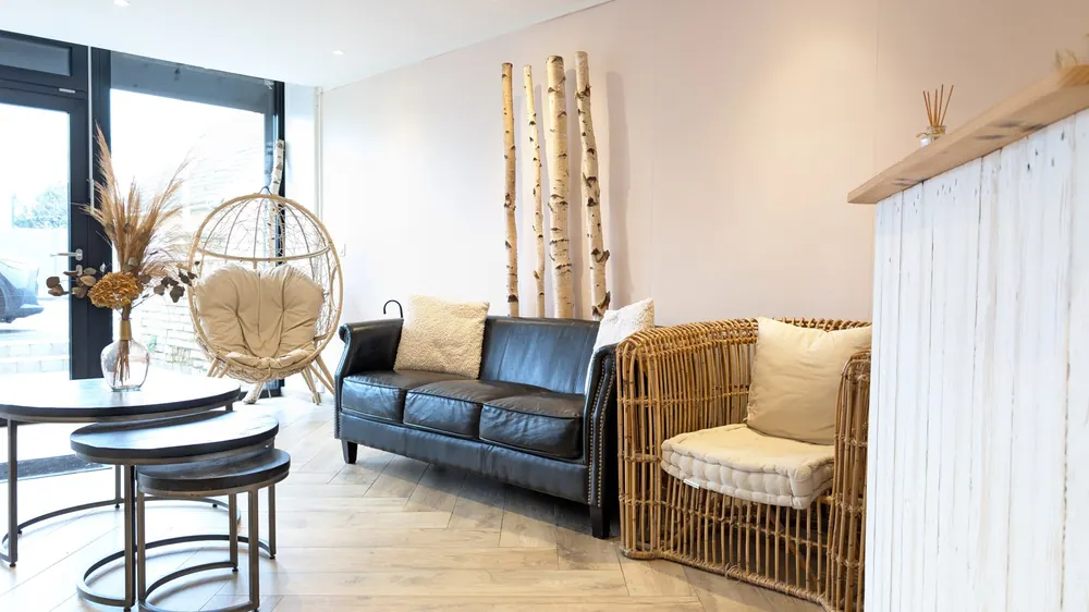 Le coin détente avec canapé et fauteuil suspendu en rotin — salon de coiffure à Calais