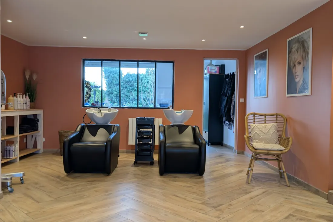 Le mur terracotta et le fauteuil en rotin du salon — coiffeur à Calais